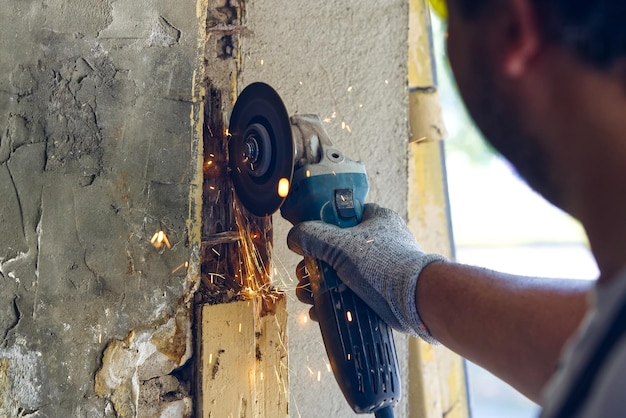 Giovane maestro che ripara le vecchie porte del garage tuttofare che ripara un edificio di legno marcio