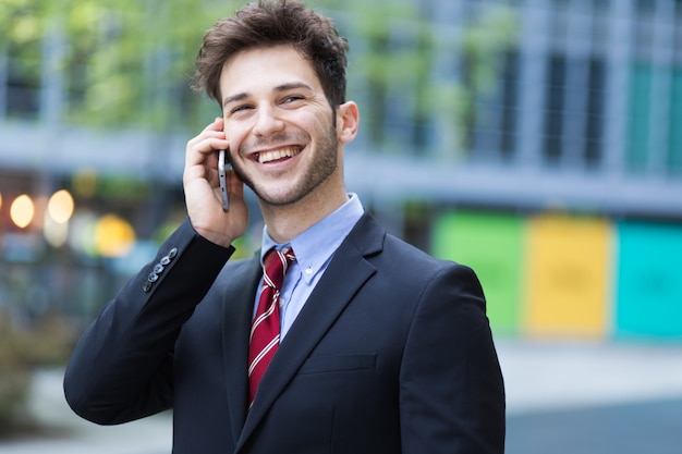 Giovane manager al telefono all&#39;aperto in un contesto urbano