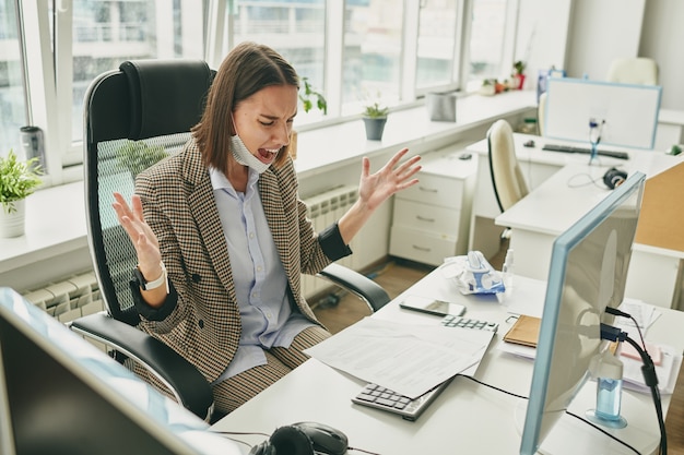 Giovane manager donna infastidita che urla in un ufficio vuoto quando ha scoperto un problema con il contratto durante l'isolamento del coronavirus