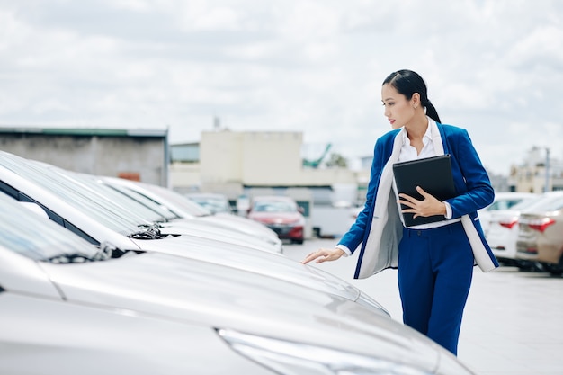 Giovane manager vietnamita di concessionaria auto che controlla le auto in vendita