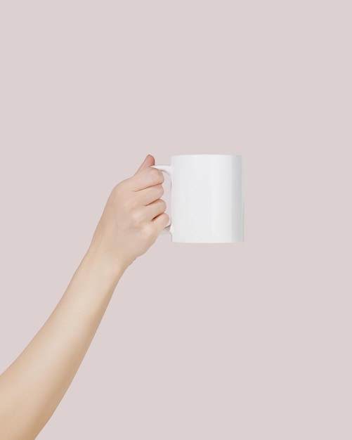 Giovane mano femminile che tiene tazza bianca su sfondo rosa Mockup