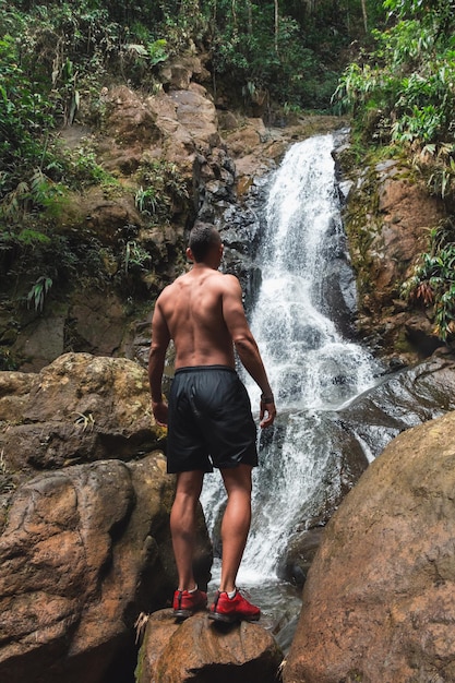 Giovane maschio che esamina una bella cascata durante il giorno