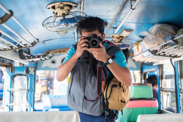 Giovane maschio che prende una foto con la macchina fotografica sul bus