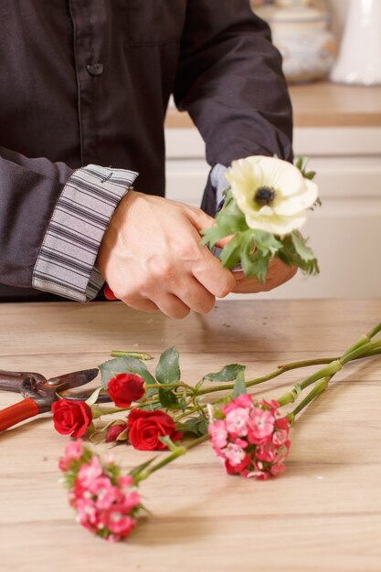 Giovane maschio fioraio il taglio di fiori al negozio di fiori, primi piani