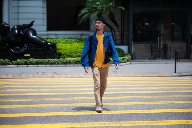 Giovane maschio hipster in abbigliamento casual che cammina lungo il sentiero mentre distoglie lo sguardo