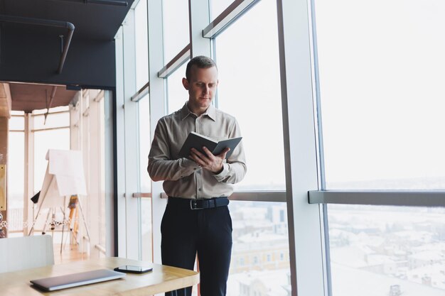 Giovane maschio intelligente che utilizza il laptop per prendere appunti durante il programma di formazione online libero professionista maschio esperto seduto con la tecnologia all'interno del bar Giovane uomo d'affari