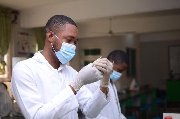 Giovane medico africano bello che analizza il campione di un esperimento nel suo laboratorio