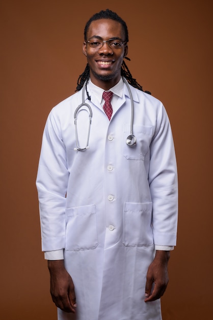 Giovane medico africano bello dell'uomo contro fondo marrone