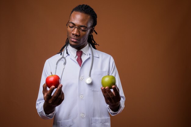 Giovane medico africano bello dell'uomo contro fondo marrone