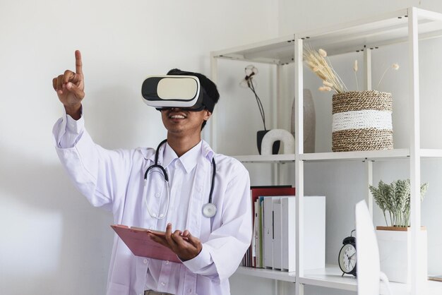 Giovane medico asiatico che indossa occhiali vr auricolare guardando e toccando la mano nella moderna clinica dell'ufficio