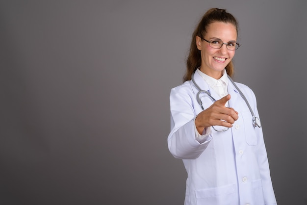 Giovane medico bella donna su sfondo grigio