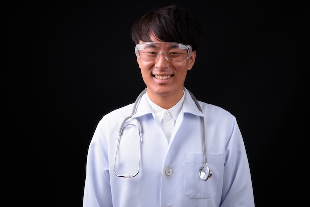 giovane medico bello uomo asiatico indossando occhiali protettivi su fondo nero