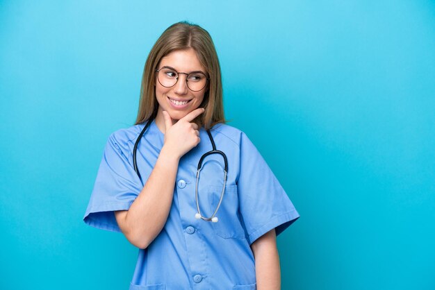 Giovane medico chirurgo donna isolata su sfondo blu che guarda al lato