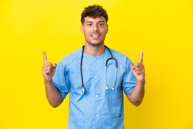 Giovane medico chirurgo uomo isolato su sfondo giallo che indica una grande idea