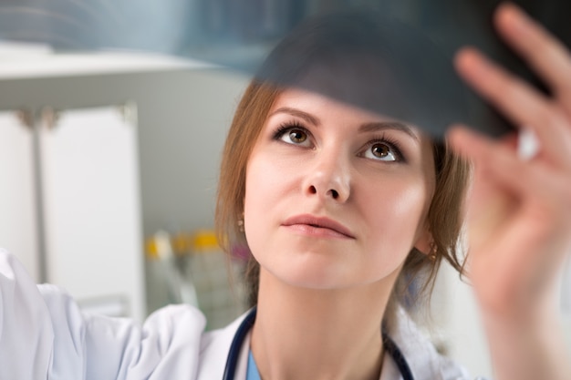 Giovane medico femminile che esamina l'immagine dei raggi x dei polmoni. Sanità e concetto medico