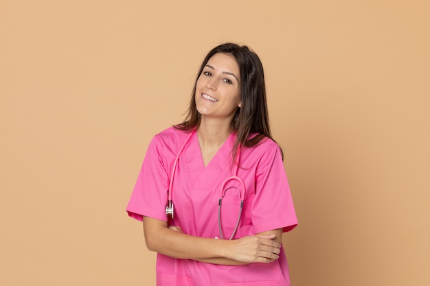 Giovane medico femminile con un'uniforme rosa che gesturing sopra la parete marrone