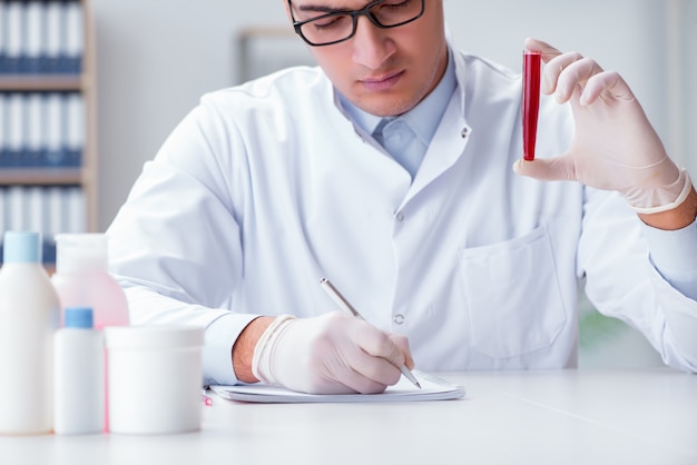 Giovane medico in laboratorio con tubo rosso