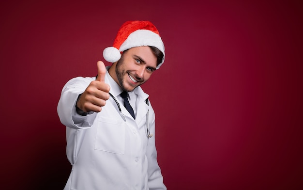 Giovane medico in uniforme bianca e cappello di Babbo Natale