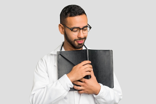 Giovane medico latino che tiene un libro isolato