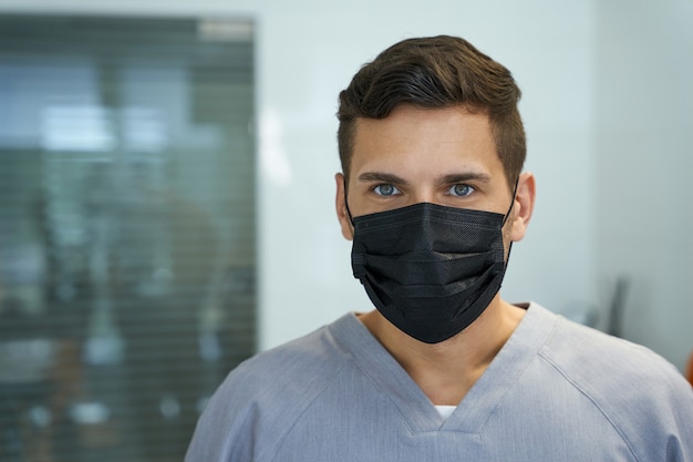 Giovane medico maschio che indossa maschera e posa per la macchina fotografica