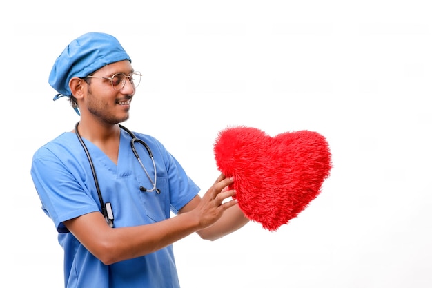 Giovane medico maschio che tiene in mano una bellissima forma di cuore rosso