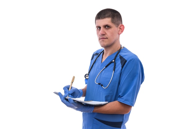 Giovane medico maschio in uniforme con documento di scrittura dello stetoscopio isolato su priorità bassa bianca.