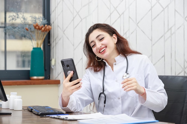 Giovane medico seduto in ufficio e parlando al telefono Foto di alta qualità