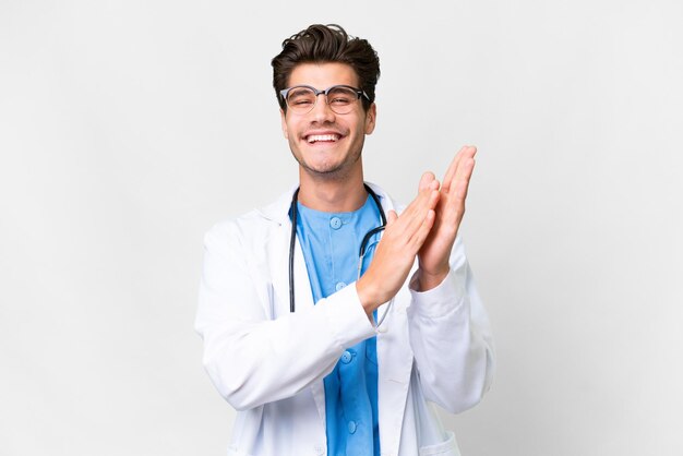 Giovane medico su sfondo bianco isolato che applaude dopo la presentazione in una conferenza