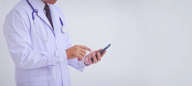 Giovane medico uomo che indossa un camice bianco utilizzando uno smartphone