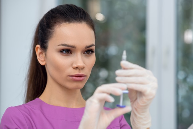 Giovane medico utilizzando una siringa in una clinica