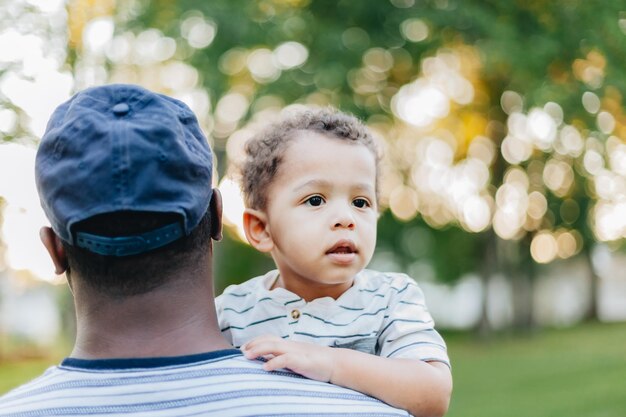 Giovane millenario afro-americano padre e razza mista figlio diversificato legamento al parco giorno d'estate