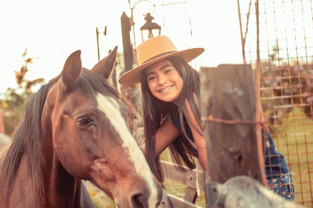 Giovane modella accanto a un cavallo e un cappello da campo
