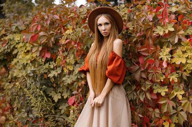 Giovane modello attraente in abiti autunnali con trucco vicino alle foglie d'autunno. avvicinamento. moda in autunno. blog