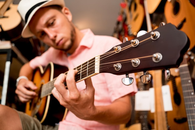 Giovane musicista che accorda una chitarra classica in un negozio di chitarre