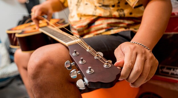 Giovane musicista che cambia le corde di una chitarra classica in un negozio di chitarre