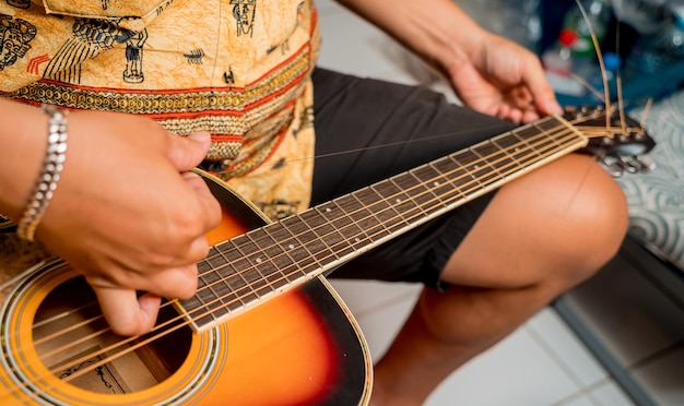 Giovane musicista che cambia le corde su una chitarra classica in un negozio di chitarre