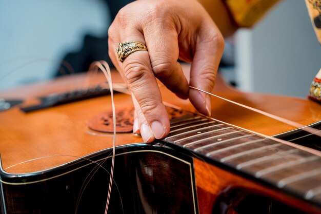 Giovane musicista che cambia le corde su una chitarra classica in un negozio di chitarre