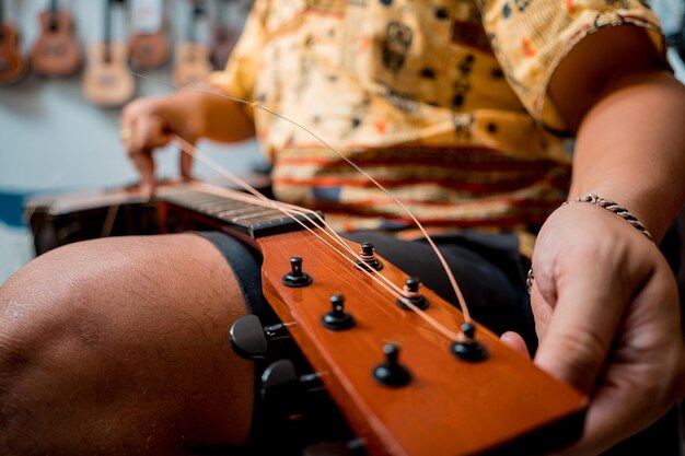 Giovane musicista che cambia le corde su una chitarra classica in un negozio di chitarre