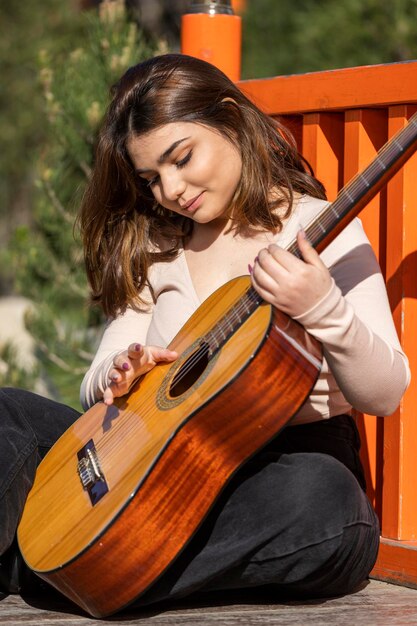 Giovane musicista che suona la chitarra al parco Foto di alta qualità