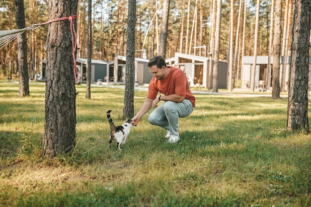 Giovane nel parco che accarezza il gatto