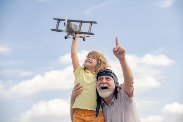 Giovane nipote e vecchio nonno che giocano con l'aereo giocattolo sullo sfondo del cielo estivo