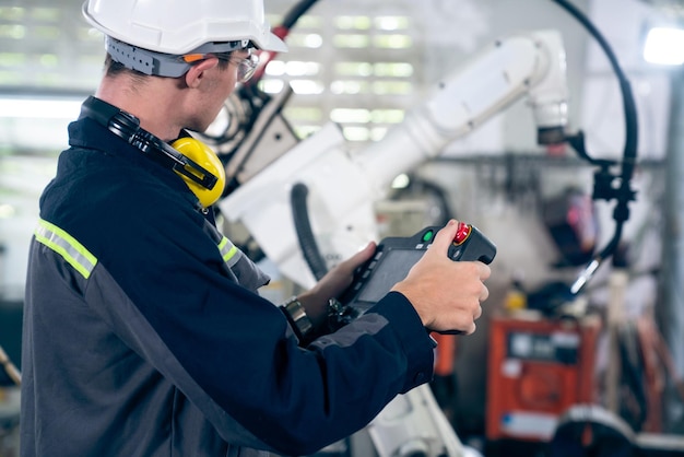 Giovane operaio di fabbrica che lavora con un abile braccio robotico