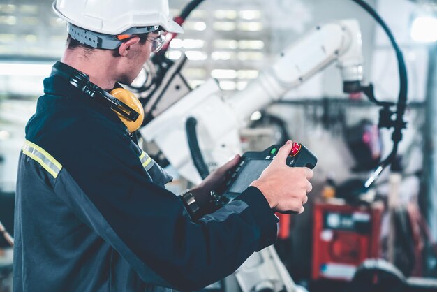 Giovane operaio di fabbrica che lavora con un abile braccio robotico