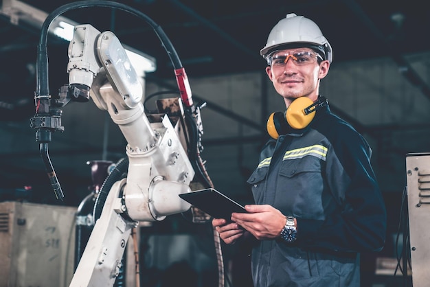 Giovane operaio di fabbrica che lavora con un abile braccio robotico