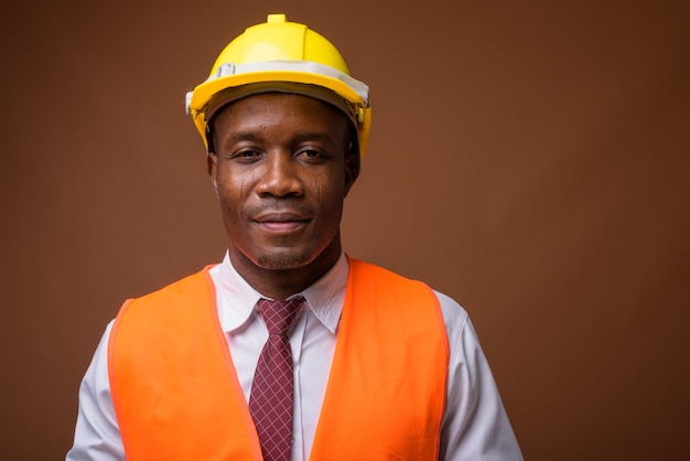 Giovane operaio edile africano dell'uomo su sfondo marrone