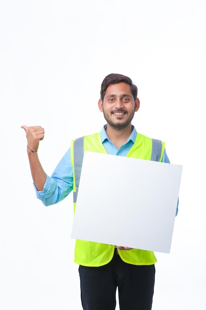 Giovane operaio edile indiano che mostra la scheda poster vuota su sfondo bianco.