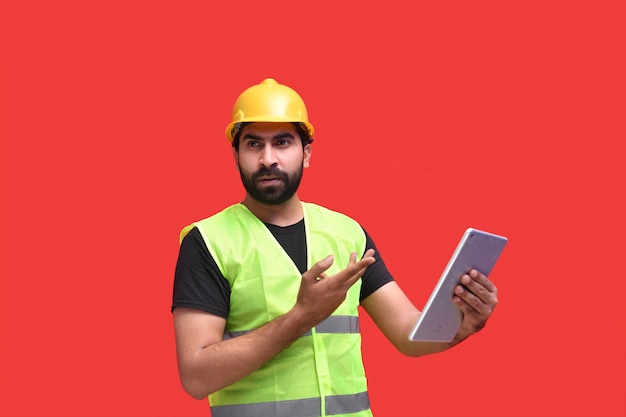 giovane operaio edile tenendo la linguetta su sfondo rosso modello pakistano indiano