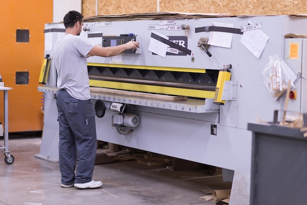 Giovane operaio lavora in una fabbrica per la produzione di mobili in legno