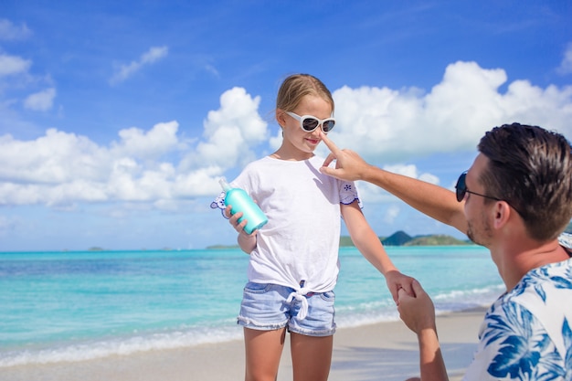 Giovane padre che applica la crema solare alla figlia