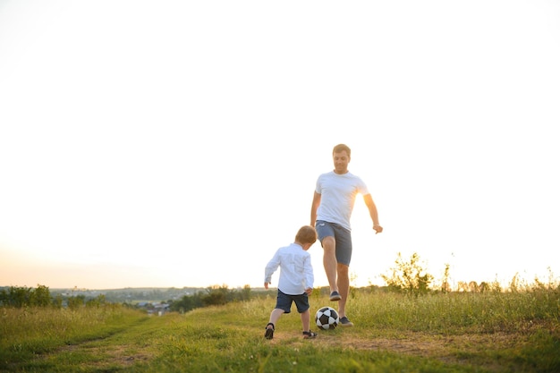 Giovane padre con il suo figlioletto che gioca a calcio la festa del papà